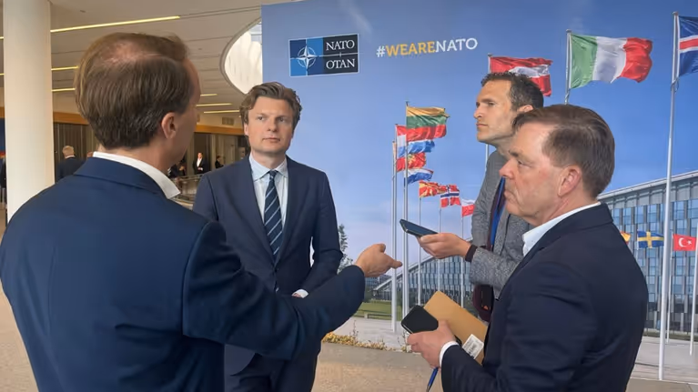 De minister in gesprek met journalisten.